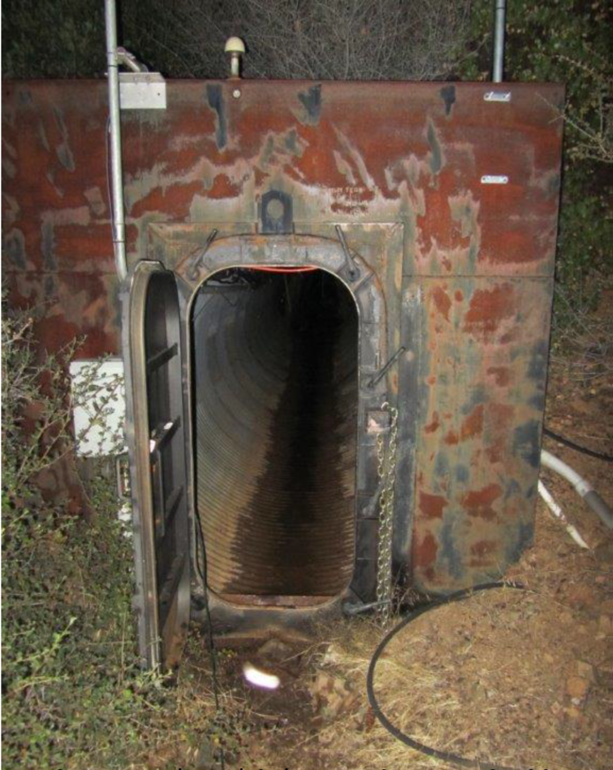 A rusty bunker-looking building with the door open. 